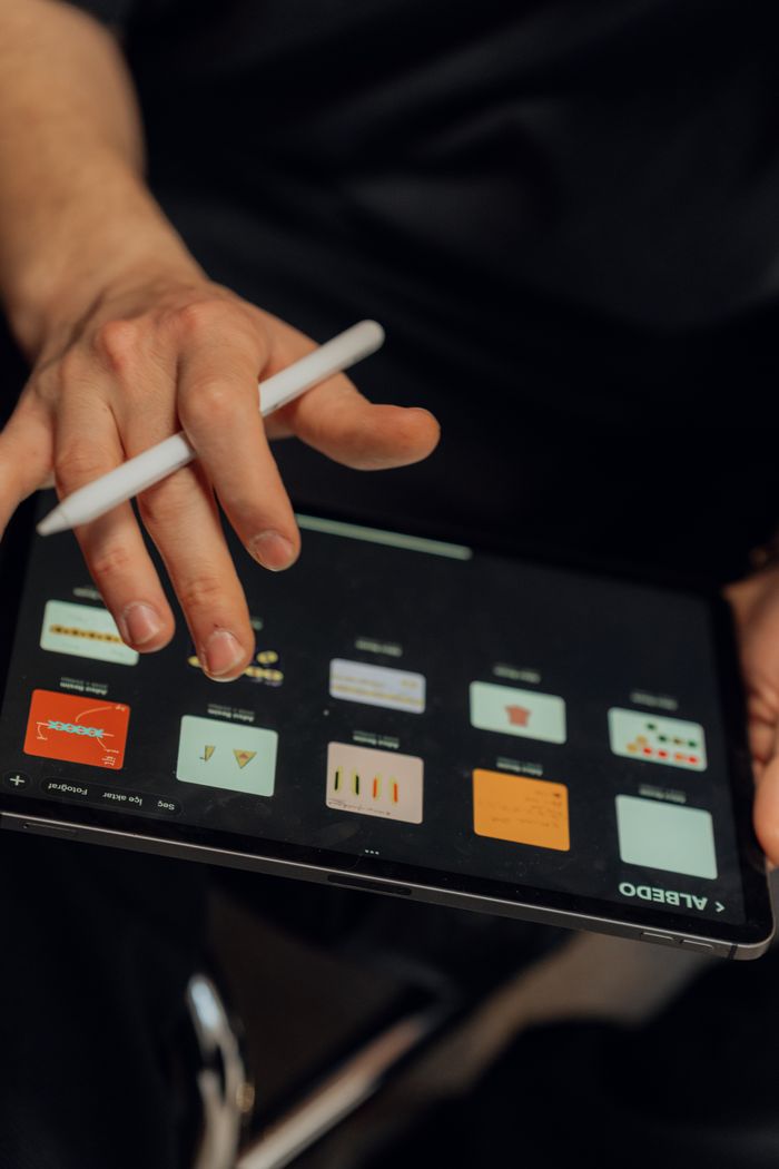 Services A person working on a digital tablet with a stylus, creating designs using an application.